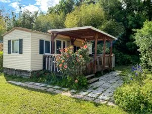 Mobil-home avec terrasse entouré de fleurs au Camping Les Avenières